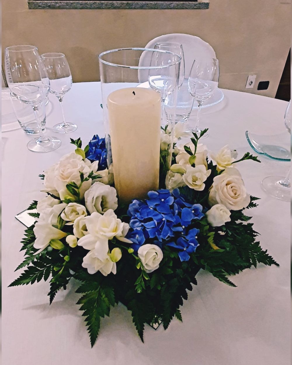 Centrotavola con ortensie blu, rose bianche e candela